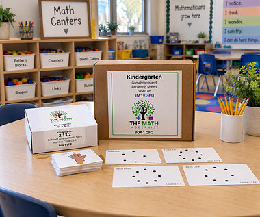 The Kindergarten v.360 kit on a classroom table: the outer box labeled Gameboards and Recording Sheets, a labeled inner box for lesson 2.13.2, a banded stack of image cards and four Circle Cards laid out ready to use.